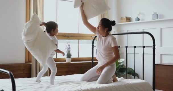 Lustige kleine asiatische Tochter und Mutter spielen Kissen im Bett — Stockvideo