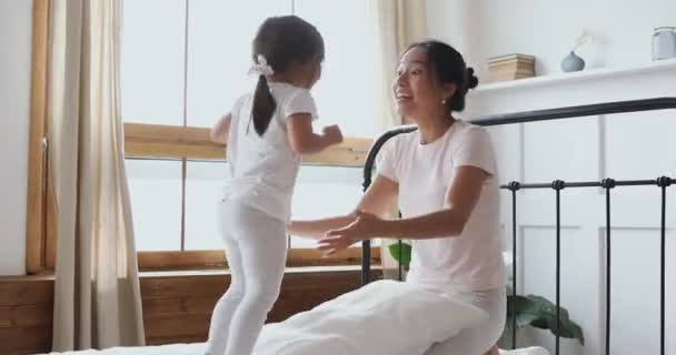 幸せなベトナム人の母親と子供の娘再生笑いでベッド — ストック動画