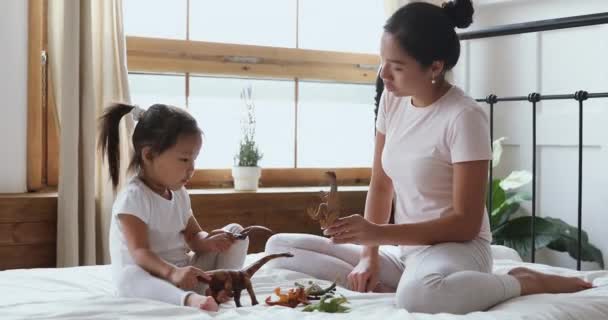 Asijské maminka s dítě dcera hrát hračky sedět v posteli — Stock video