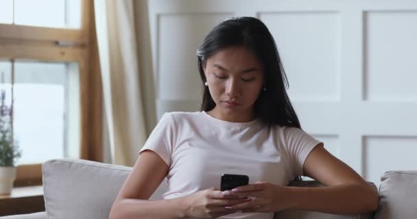 Захоплена азіатська леді тримає смартфон вражений мобільною перемогою — стокове відео