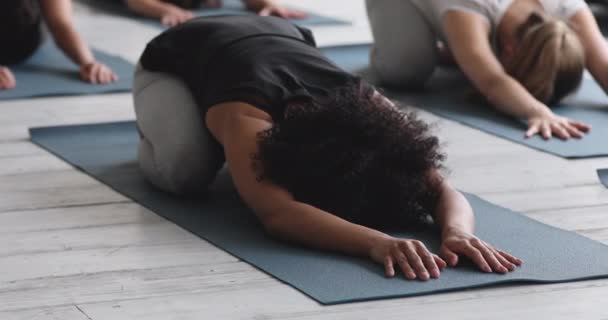 African woman performing Child pose with associates during yoga class — Stock Footage African woman performing Child pose with associates during yoga class Video Clip