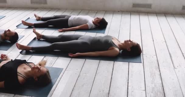 Gruppe von Menschen, die Yoga praktizieren und Asana für Leichenteile machen — Stockvideo