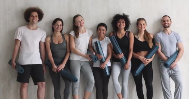 Multi-ethnic millennial people standing holding yoga mats posing for camera — Stock Footage Multi-ethnic millennial people standing holding yoga mats posing for camera Royalty Free Stock Footage