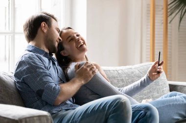 Mutlu milenyum çifti cep telefonuyla selfie çekerken gülümser.