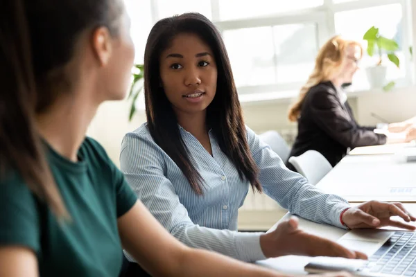 Afrikansk kontorsarbetare hjälper till att lärling sitter vid delat skrivbord — Stockfoto