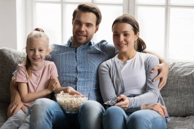 Mutlu ebeveynler ve küçük kız film izlerken abur cubur yerler.