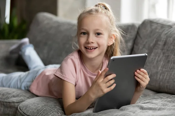 Smiling little girl playing game on modern tablet — Stock Photo, Image