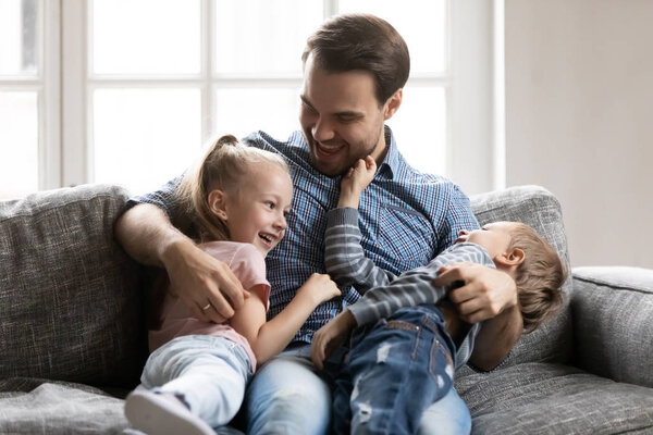 Счастливый молодой папа веселится, играя с детьми.
