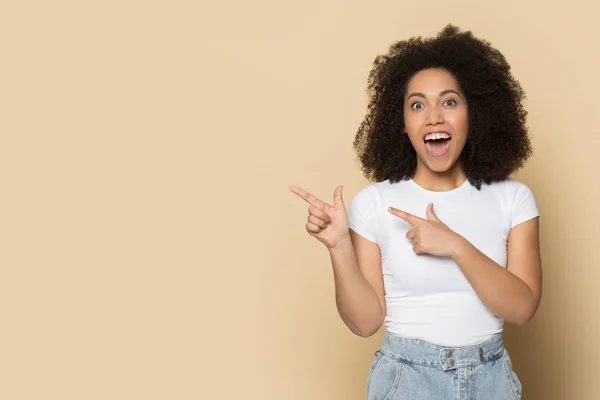 Surprised young african american girl pointing fingers on copy space. — Stock Photo, Image