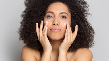 Young african american woman applying professional skincare product. clipart