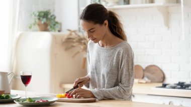 Genç, melez, sakin kadın salata için taze sebze doğruyor..