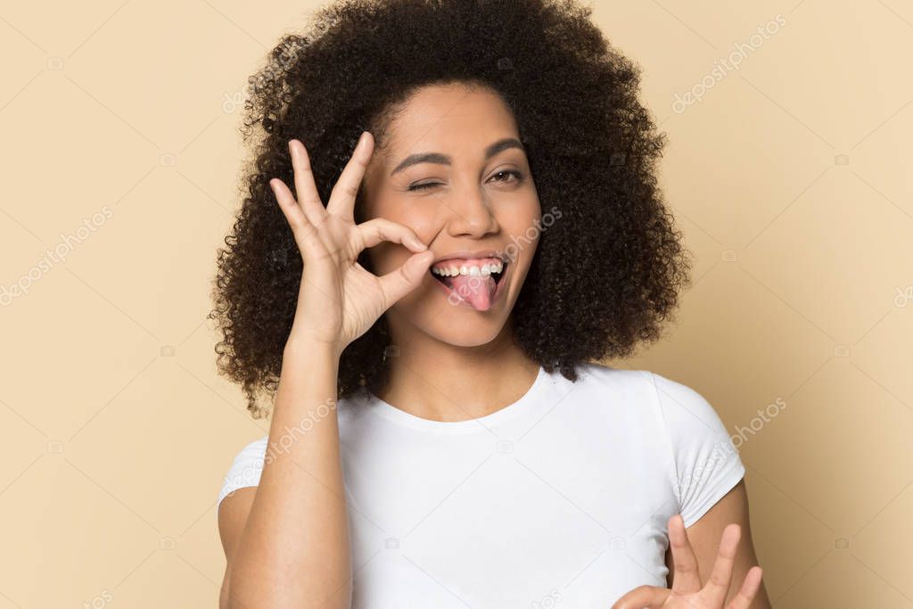 Joyful african american sly young woman showing ok gesture.