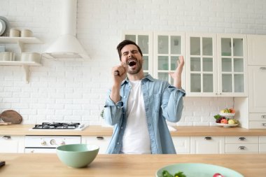 Mutfak gereçlerini mikrofon olarak kullanan aşırı neşeli genç adam..