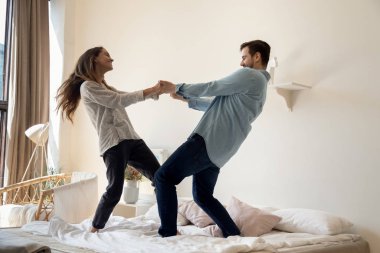 Mutlu bir aile çifti yatakta favori müzikle dans ediyor..