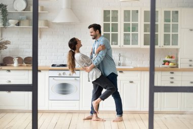 Uzun boylu, yakışıklı bir genç adam, gülümseyen karısını kucaklıyor ve düşürüyor..