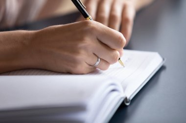 Genç bir kadın not defterine el yazısı yazmış.