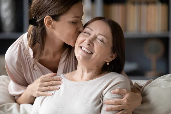 Loving adult daughter kiss senior mother relaxing together — Stock Photo, Image