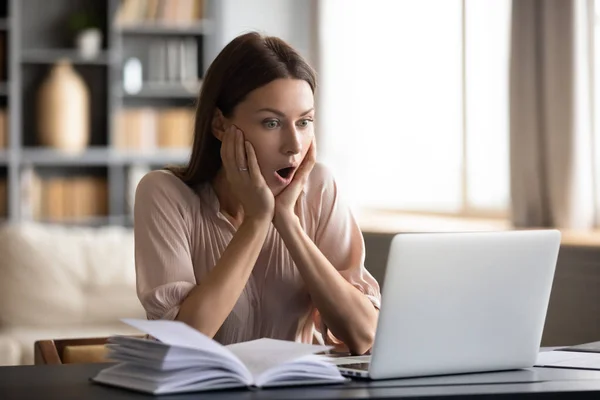 Mujer joven asombrada leer noticias inesperadas en línea — Foto de Stock