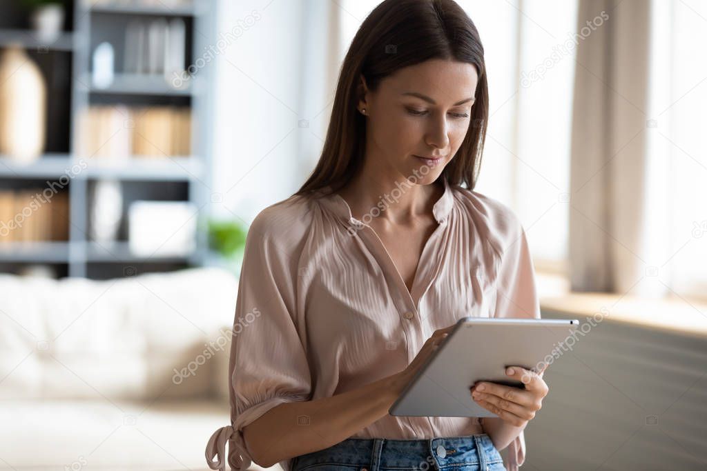 Young woman busy browsing web on modern tablet gadget