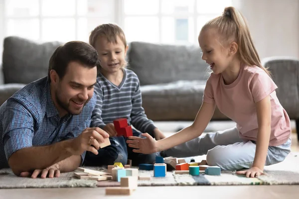 Papá joven jugando con niños construyendo con ladrillos — Foto de Stock