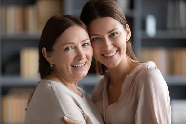 Portrait of smiling adult mom and daughter posing together