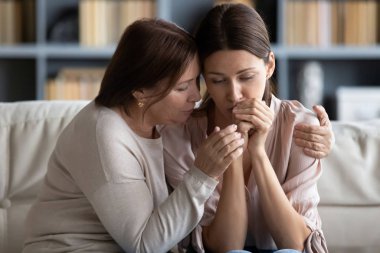 Orta yaşlı bir anne strese girmiş kızını kucaklıyor.