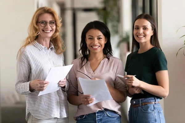 Attractive multi-ethnic businesswomen posing standing in office hallway — Stock Photo, Image