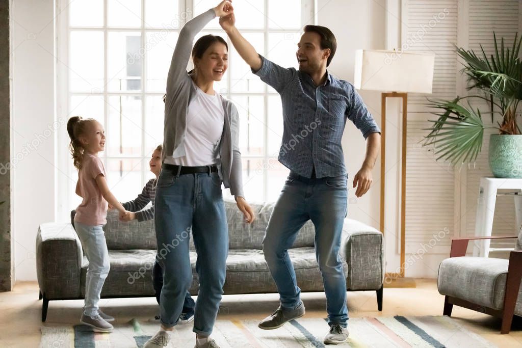 Happy young family with kids dancing together at home