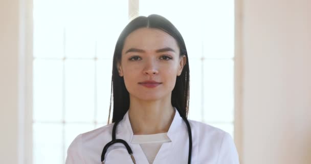 Mujer joven médico o enfermera mirando a la cámara, primer plano retrato — Vídeos de Stock