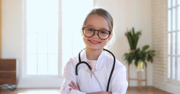 Κορίτσι παιδί φορούν ιατρική παλτό κοιτάζοντας κάμερα παίζοντας το γιατρό — Αρχείο Βίντεο