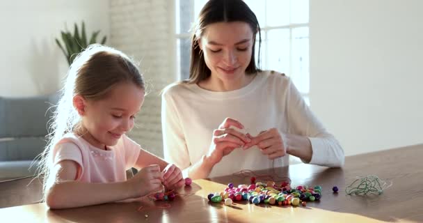 Roztomilý školka dcera making náhrdelník s mladý maminka hlídání — Stock video