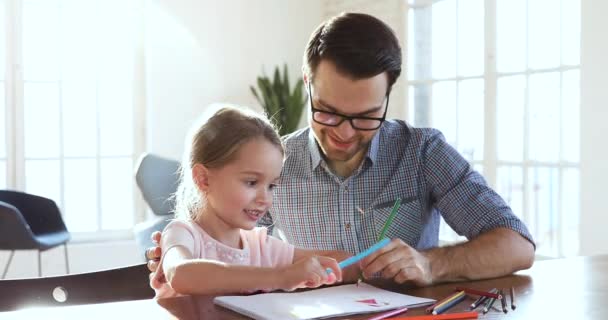 Счастливый папа учит маленькую милую девочку рисовать цветными карандашами — стоковое видео