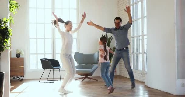 Actieve zorgeloze ouders en kind dochter dansen samen thuis — Stockvideo