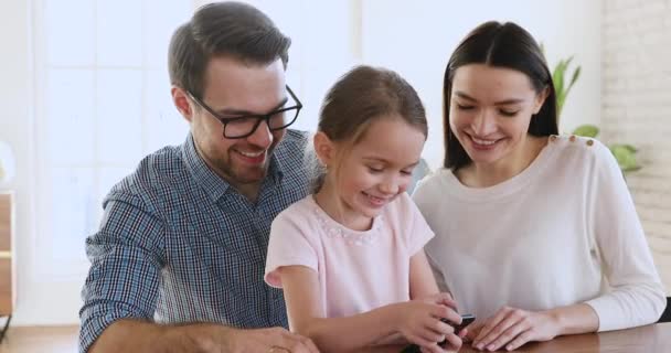 Милая дочь, держащая смартфон, показывает родителей, смотрящих смешное видео — стоковое видео