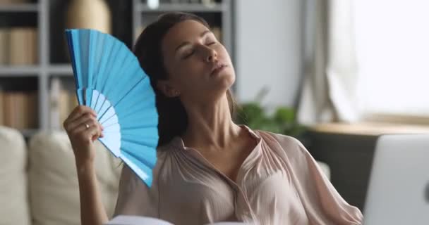 Overheated sweaty young woman waving fan sit at home office — ストック動画