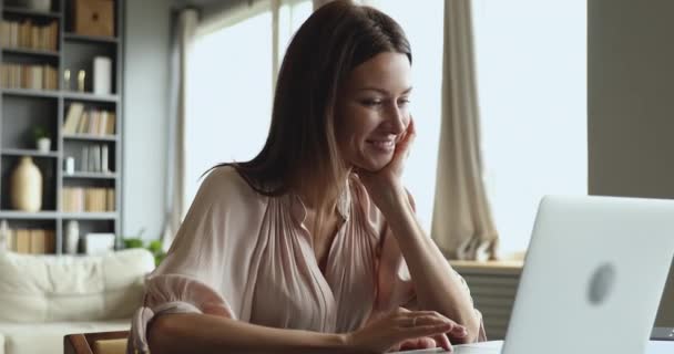 Usmívající se atraktivní mladá žena psaní na notebooku sedět u stolu — Stock video