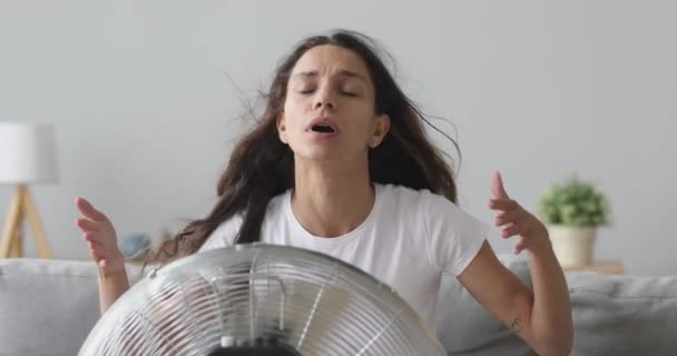 Oververhit jong gemengd ras meisje zitten in de voorkant van ventilator. — Stockvideo