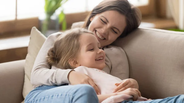 Sonriente madre y adorable hijita relajándose juntos en el sofá — Foto de Stock