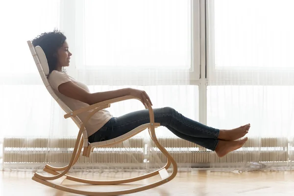 Relaxed african woman resting on wooden rocking chair — Stock Photo, Image