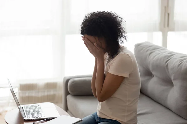 African woman sitting near computer cover face with hands crying — Stock Photo, Image