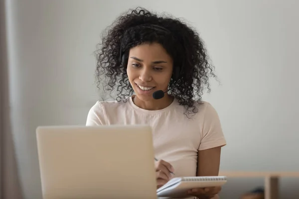 Afrikaanse vrouw in headset kijken naar computer doen online taak — Stockfoto