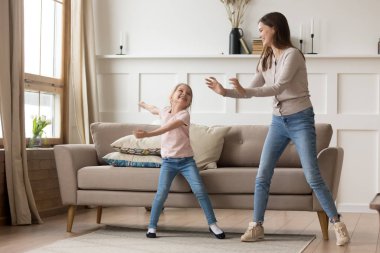 Mutlu genç anne evde kızıyla dans ediyor.