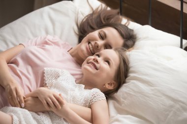 Küçük tatlı kızı olan mutlu bir anne yatakta dinleniyor.