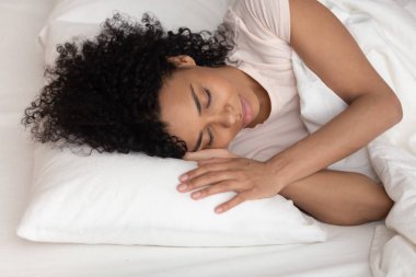 Yatakta yalnız uyuyan Afrikalı bir kadın.