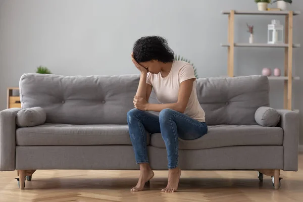 Africano femmina piangendo si sente infelice seduta su divano a casa — Foto Stock
