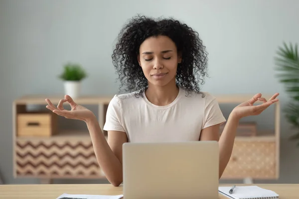 Mujer africana meditando sentada en el escritorio frente a la computadora portátil — Foto de Stock