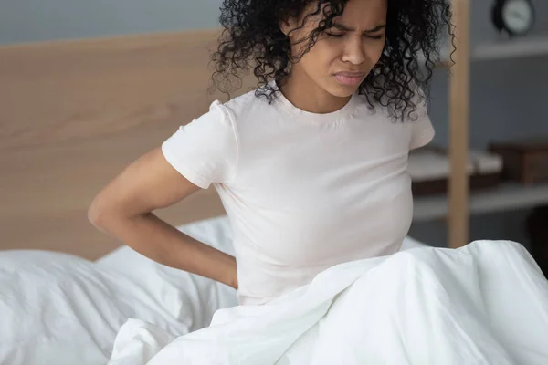 African woman feeling lower back pain after sleeping — Stock Photo, Image