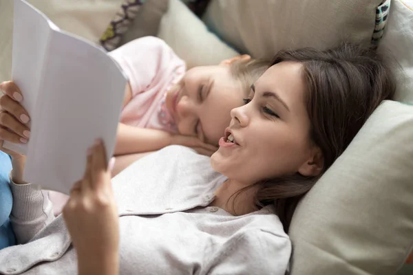 Любляча мати читає книгу для сонної милої маленької дочки — стокове фото