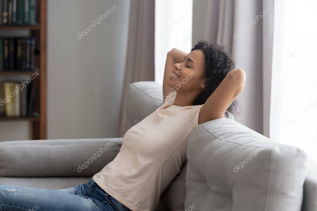 Side view serene african woman leaned on couch resting