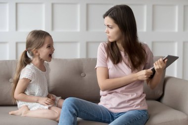 Strict mother scolding little daughter for long computer tablet use clipart